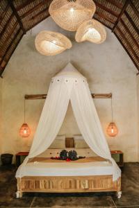 a bedroom with a bed with curtains and chandeliers at Owa Lodge Areguling in Kuta Lombok