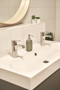 a bathroom sink with two faucets and a mirror at Cityloft - im Zentrum, inkl Parkplatz, Netflix, 3-Raum in Leipzig +19 photos