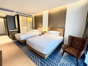una habitación de hotel con 2 camas y una silla en Four Points by Sheraton Chongqing, Yongchuan, en Yongchuan