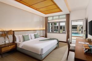 a bedroom with a large white bed and a desk at The Mahata in Legian