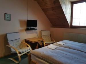 a bedroom with two chairs and a bed and a tv at Privát Kováč in Tatranská Lomnica