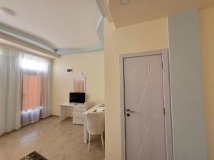 a room with a door and a table and a television at Китанови- стаи за гости in Sliven