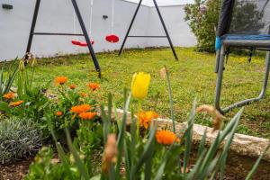 a garden with orange and yellow flowers and a chair at Villa Gabi in Pridraga