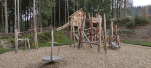 un parque infantil con un tobogán de madera y un columpio en Ferienwohnung "An den Kurwiesen", en Masserberg