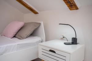 a white bedroom with a bed and a lamp on a night stand at Villa Gabi in Pridraga