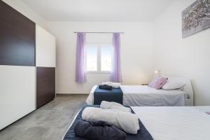 two beds in a room with purple curtains at Villa Gabi in Pridraga