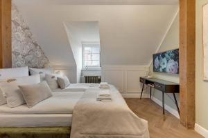 a bedroom with a large white bed and a television at Downtown Apartments The Love Bridge - Na Piaskach in Gdańsk