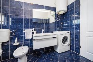 a blue tiled bathroom with a washer and dryer at Villa Gabi in Pridraga