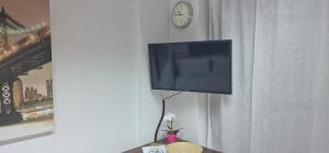 einen Flachbild-TV, der an einer Wand mit einer Uhr hängt in der Unterkunft Cosy studio in Pilea Thessaloniki in Thessaloniki