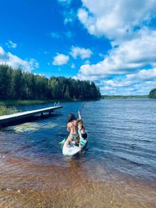 mężczyzna i kobieta na desce wiosłowej w wodzie w obiekcie Cottage Elsa w mieście Kuopio