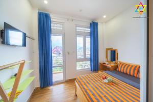 a bedroom with blue curtains and a bed and a television at Villa Tuan Vu Da Lat Grand in Da Lat