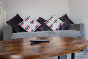 a couch with pillows and a remote control on a table at Wester-Moor comfy modern house in Barnstaple by StayStay com in Barnstaple