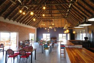 un restaurant avec des tables et des chaises et un mur en briques dans l'établissement Klein Karoo Game Lodge, à Oudtshoorn