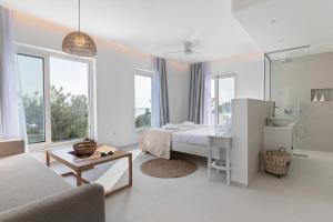 a white bedroom with a bed and a couch at serene villas in Ierápetra
