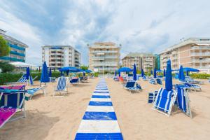 una spiaggia con sedie blu e ombrelloni blu di Residence Solmare Immobiliare Pacella a Lido di Jesolo