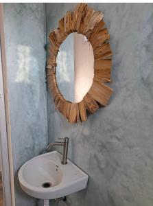 baño con lavabo y espejo en la pared en Fisherman Lodge, en Paje
