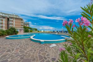 a swimming pool in a resort with pink flowers at Residence Solmare Immobiliare Pacella in Lido di Jesolo