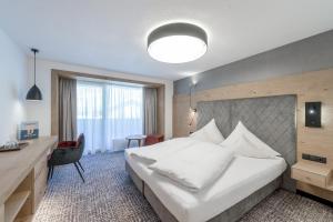 a hotel room with a bed and a desk at Hotel Grauer Bär in Sölden