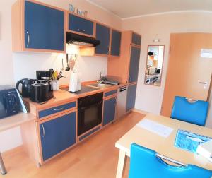 een kleine keuken met blauwe kasten en een tafel en stoelen bij Ostseestrand in Juliusruh