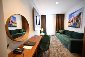 a living room with a couch and a table and a mirror at Hotel Tamiš & Spa in Pančevo