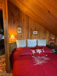 a bedroom with a red bed with wooden walls at Sirolane, chalet au bord des pistes au Sauze in Enchastrayes