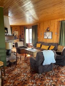 ein Wohnzimmer mit einem Sofa, Stühlen und einem Tisch in der Unterkunft Sirolane, chalet au bord des pistes au Sauze in Enchastrayes