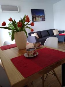 una mesa con dos tazas y un jarrón con flores en APARTAMENT MARTA, en Biłgoraj