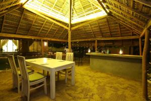 ein Esszimmer mit einem Tisch und Stühlen unter einem Dach in der Unterkunft The Beach house by Kay Jay Hotels in Pasikuda