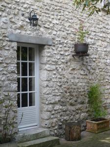 a stone building with a white door and a window at Le Havre de Bennecourt in Bennecourt