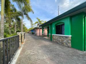 un edificio verde junto a una calle con palmeras en Poracay Resort powered by Cocotel, en Porac