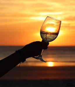 una persona sosteniendo una copa de vino con una puesta de sol en el fondo en Hotel Cafe La Morena, en Fuengirola