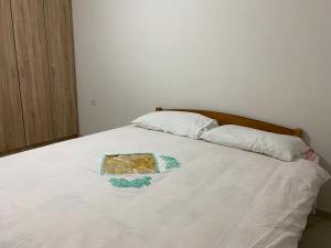 Una cama blanca con dos almohadas y un plato. en Art villa, en Durrës