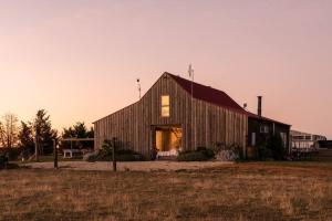 a large wooden barn with the door open in a field at The Barn Heathcote in Heathcote