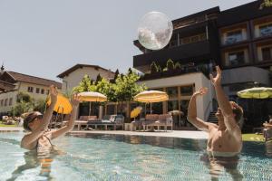 two people playing with a ball in a swimming pool at Mari Pop Hotel in Ried im Zillertal