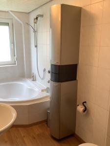a bathroom with a tub and a sink and a refrigerator at Ferienwohnung SCHWARZACHHÖHE nur für Erwachsene in Wendelstein