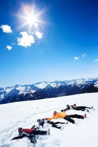 un grupo de personas yaciendo en la nieve en una montaña en Apartmenthaus Maximilian, en Neukirchen am Großvenediger