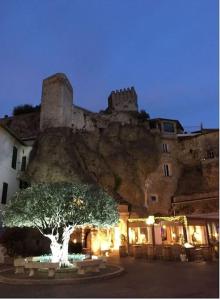 um castelo sentado no topo de uma montanha com uma árvore em Village Médiévale, superbe appartement vu mer et Monaco em Roquebrune-Cap-Martin