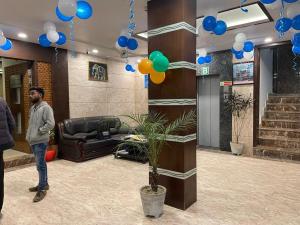 un hombre parado en un vestíbulo con globos azules y verdes en Hotel Areeba by The Golden Taj Group & Hotels en Agra