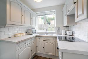 a white kitchen with white cabinets and a window at Stylish & Comfortable 3BR Spacious Home with Parking in Greenhill
