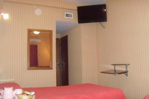 a bedroom with a red bed and a television on the wall at Hotel Embajador in Rosario