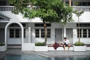 a man sitting on a bench in front of a house at The Mahata in Legian