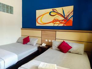 Cette chambre comprend deux lits et un tableau mural. dans l'établissement Ahlen Pangandaran, à Pangandaran