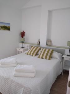 1 dormitorio con 1 cama blanca y 2 toallas en Ático, Islantilla, en Islantilla