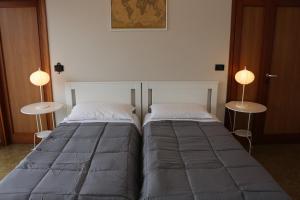 two beds in a room with two lamps on tables at EasyRoom Schio in Schio
