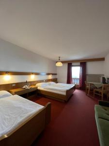 セルヴァ・ディ・ヴァル・ガルデーナにあるRifugio Fraraのベッド2台とテーブルが備わるホテルルームです。