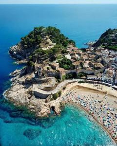 an island with a beach with umbrellas and the ocean at Portal 17 Can Tort in Tossa de Mar