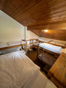 a room with three bunk beds and a wooden ceiling at Rifugio Frara in Selva di Val Gardena