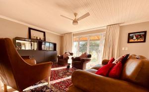 uma sala de estar com mobiliário de couro e uma ventoinha de tecto em Primo farm em Paarl