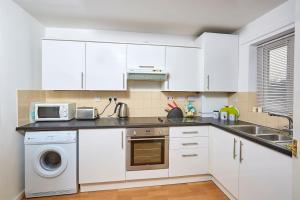 a kitchen with white cabinets and a microwave at Shirebrook House Coventry in Foleshill