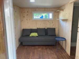 a couch in a tiny house with a window at Camping le Petit Liou Sites & Paysages in Baratier
